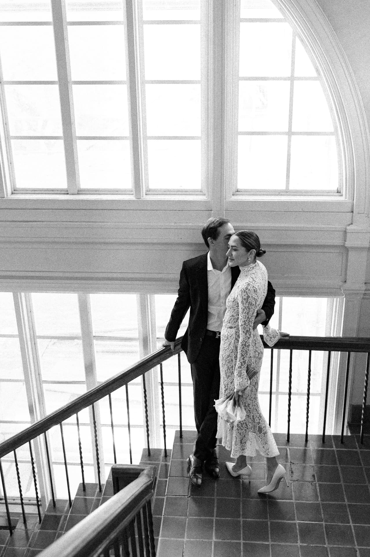 The couple on a staircase by tall windows